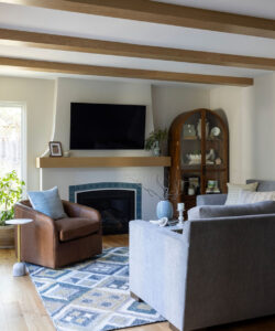 Living room in a San Jose home with exposed wood beams, a corner fireplace with blue tile trim and a leather swivel chair
