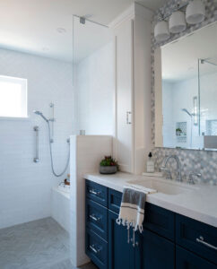 Remodeled bathroom in a San Jose home with a navy blue vanity, hexagon tile backsplash and a white tile walk-in shower