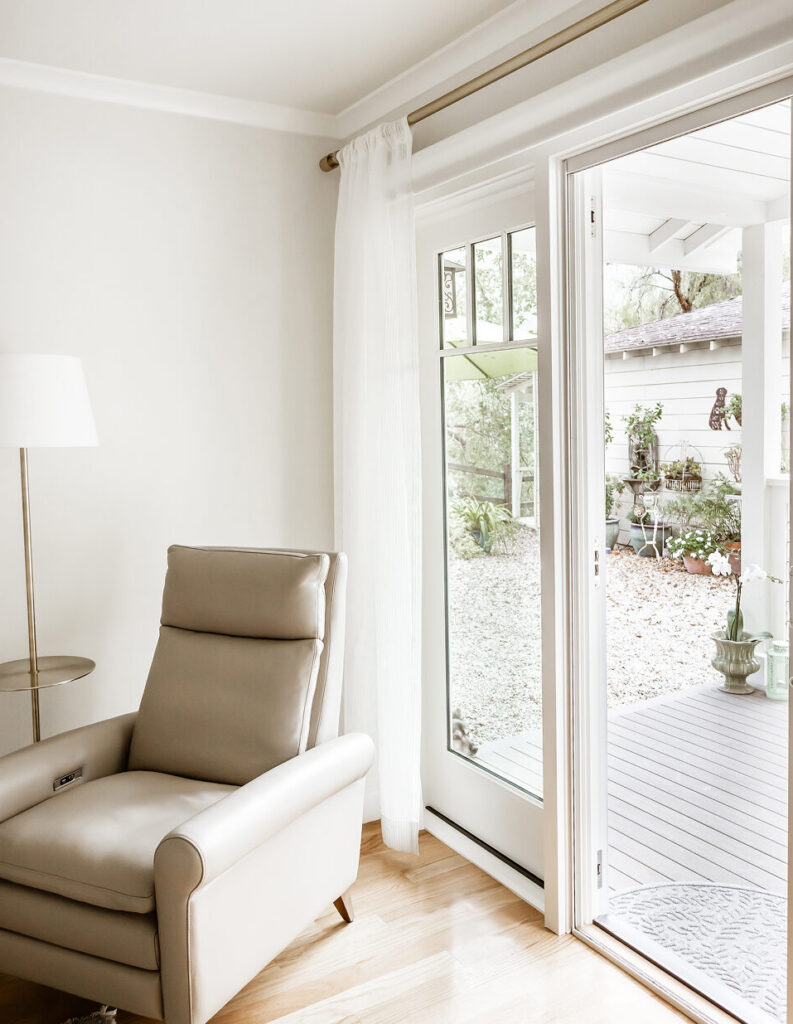 Sitting corner with a tan leather recliner and floor lamp beside a glass door opening to a garden deck